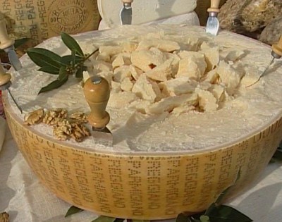 Immagine forma di Parmigiano Reggiano con scaglie e tipico coltellino "a mandorla" e gherigli di noci